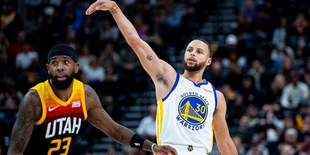 Golden State Warriors guard Stephen Curry (30) holds his follow-through on his shot while guarded by Utah Jazz forward Royce O'Neale (23) in the first half during an NBA basketball game Saturday, Jan. 1, 2022, in Salt Lake City.