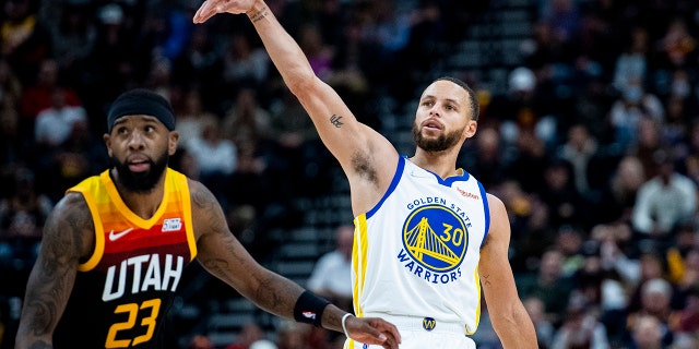 Golden State Warriors guard Stephen Curry (30) holds his follow-through on his shot while guarded by Utah Jazz forward Royce O'Neale (23) in the first half during an NBA basketball game Saturday, Jan. 1, 2022, in Salt Lake City.