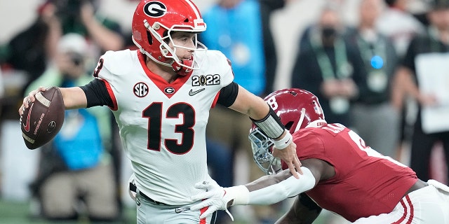 Georgia's Stetson Bennett gets away from Alabama's Christian Harris during the first half of the College Football Playoff championship football game Monday, Jan. 10, 2022, in Indianapolis.