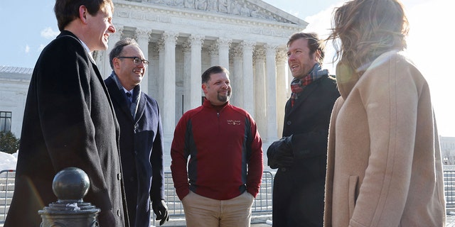 Brandon Trosclair, who owns grocery stores in Louisiana and Mississppi, poses for photos with his legal representatives before the U.S. Supreme Court hears arguments on his case against the Biden administration's nationwide vaccine-or-test-and-mask COVID-19 mandates, in Washington, Jan. 7, 2022.