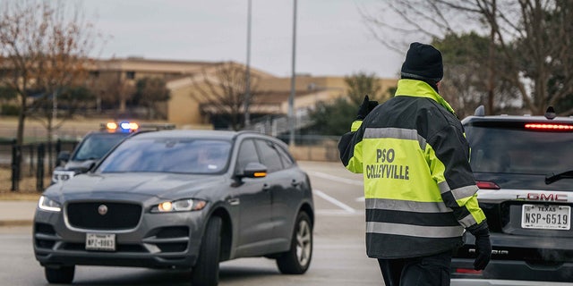 A law enforcement officer directs traffic at an intersection near the Congregation Beth Israel synagogue on Jan. 15, 2022, in Colleyville, Texas. Police responded to a hostage situation after reports of a man with a gun was holding people captive at the synagogue.