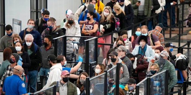 Passengers queue up to pass through the north security checkpoint Monday, Jan. 3, 2022, in the main terminal of Denver International Airport in Denver. (AP Photo/David Zalubowski)
