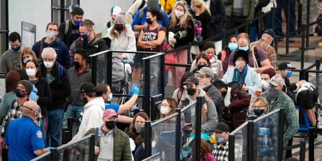 Passengers queue up to pass through the north security checkpoint Monday, Jan. 3, 2022, in the main terminal of Denver International Airport in Denver.