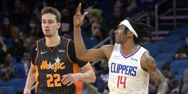 Los Angeles Clippers guard Terance Mann (14) celebrates after scoring a 3-pointer in front of Orlando Magic forward Franz Wagner (22) during the first half of an NBA basketball game, miércoles, ene. 26, 2022, en orlando, Fla.