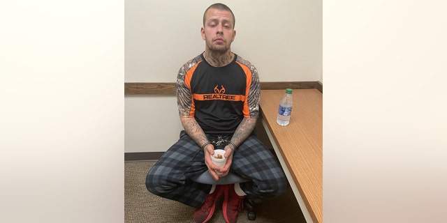 Tyler Henderson is pictured in handcuffs Sunday