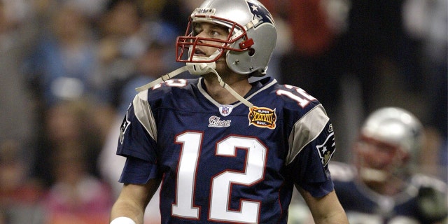 O quarterback Tom Brady do New England Patriots entra em campo durante o Super Bowl XXXVIII contra o Carolina Panthers no Reliant Stadium em 1 de fevereiro de 2004, em Houston.  Os Patriots derrotaram os Panthers por 32 a 29.