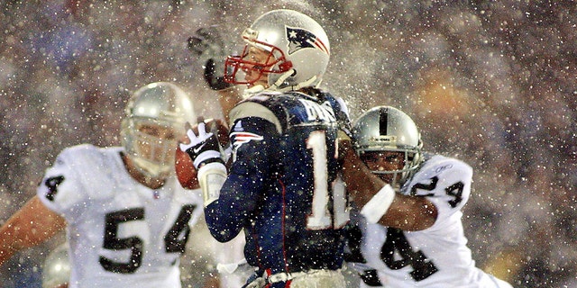 New England Patriots quarterback Tom Brady takes a hit from Charles Woodson of the Oakland Raiders on a pass attempt in the last two minutes of a game in the AFC playoffs Jan. 19, 2002, in Foxboro, Massachusetts.
