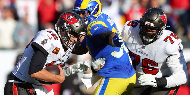 TAMPA, FLORIDA - ENERO 23: Tom Brady #12 of the Tampa Bay Buccaneers is sacked by Aaron Donald #99 of the Los Angeles Rams in the second quarter in the NFC Divisional Playoff game at Raymond James Stadium on January 23, 2022 in Tampa, Florida.