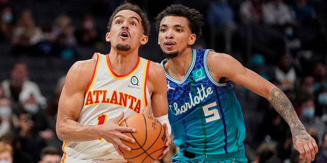 Atlanta Hawks guard Trae Young , left, drives to the basket past Charlotte Hornets guard James Bouknight (5) during the second half of an NBA basketball game Sunday, Jan. 23, 2022, in Charlotte, N.C.