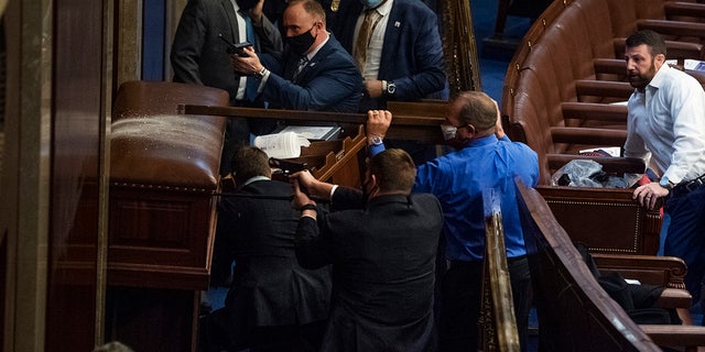 Rep. Troy Nehls, R-Texas, blue shirt, uses a sign to deter rioters as they tried to break into the House chamber to disrupt the joint session of Congress to certify the Electoral College vote Jan. 6, 2021. Rep. Markwayne Mullin, R-Okla., appears at right. (Tom Williams/CQ-Roll Call, Inc via Getty Images)