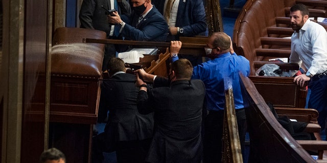 Rep. Troy Nehls, R-Texas, blue shirt, uses a sign to deter rioters as they tried to break into the House chamber to disrupt the joint session of Congress to certify the Electoral College vote Jan. 6, 2021. Rep. Markwayne Mullin, R-Okla., appears at right. (Tom Williams/CQ-Roll Call, Inc via Getty Images)