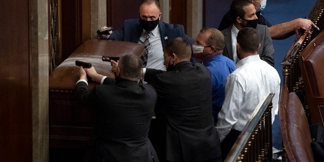 Security barricades the door of the House chamber as rioters disrupt the joint session of Congress to certify the Electoral College vote Jan. 6, 2021. Reps. Troy Nehls, R-Texas, blue shirt, and Markwayne Mullin, R-Okla., right, are also pictured. (Tom Williams/CQ-Roll Call, Inc via Getty Images)