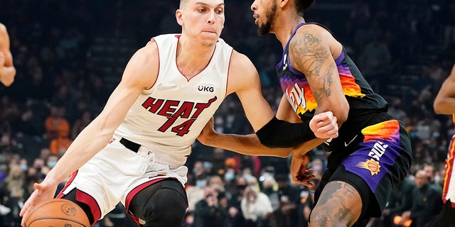 Miami Heat's Tyler Herro (14) drives around Phoenix Suns' Cameron Payne during the first half of an NBA basketball game Saturday, ene. 8, 2022, en Phoenix. 