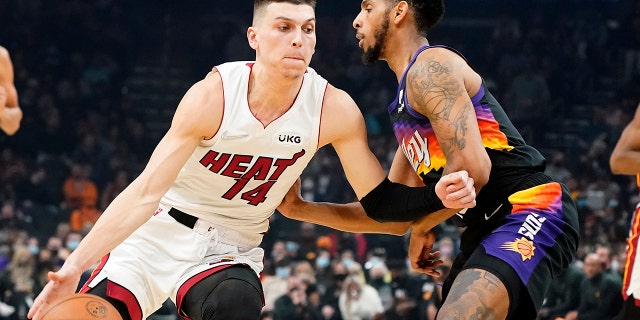 Miami Heat's Tyler Herro (14) drives around Phoenix Suns' Cameron Payne during the first half of an NBA basketball game Saturday, ene. 8, 2022, en Phoenix.