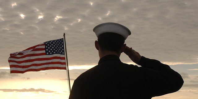 Sailors salute the American flag during the morning playing of the National Anthem before the maiden voyage of the USS San Antonio (LPD-17) amphibious transport dock after her commissioning ceremony. 