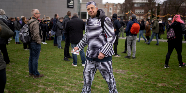 A man wearing a prisoner's suit joined hundreds of people who defied a ban Sunday to gather and protest the Dutch government's coronavirus lockdown measures, in Amsterdam, Netherlands, Sunday, Jan. 2, 2022. (AP Photo/Peter Dejong)