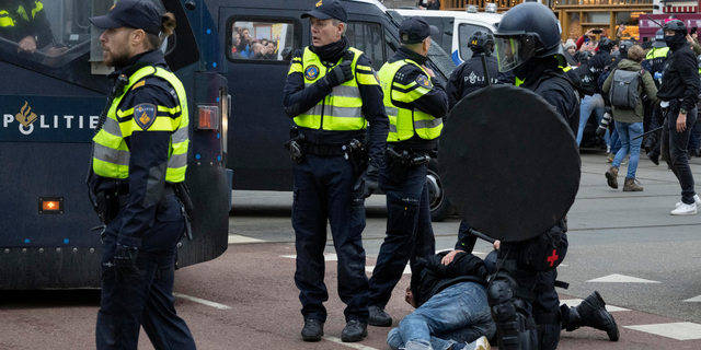 Police arrest a demonstrator as thousands of people defied a ban Sunday to gather and protest the Dutch government's coronavirus lockdown measures, in Amsterdam, Netherlands, Sunday, Jan. 2, 2022. (AP Photo/Peter Dejong)