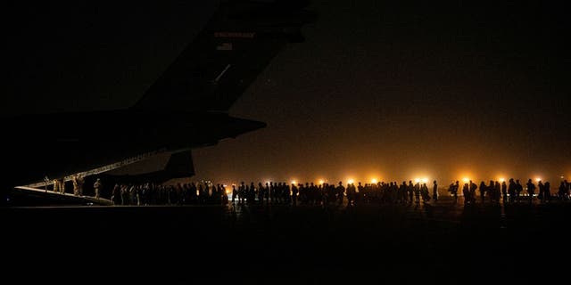 Evacuees from Afghanistan board a military aircraft during an evacuation from Kabul, in this photo taken on August 19, 2021 at undisclosed location and released on August 20, 2021. 