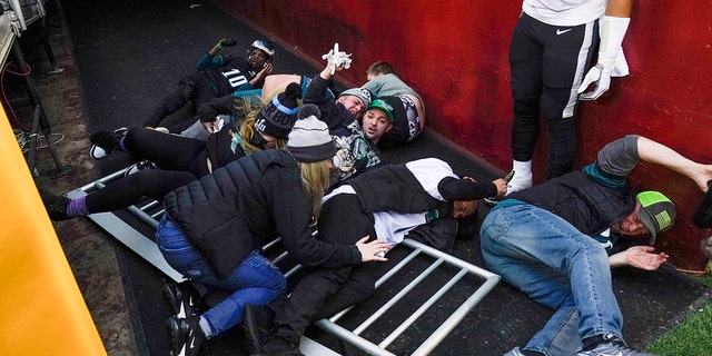 Fans lay on the ground after falling onto Philadelphia Eagles quarterback Jalen Hurts (1) as a railing collapsed following the end of an NFL football game, Sunday, Jan. 2, 2022, in Landover, Md. Philadelphia won 20-16.