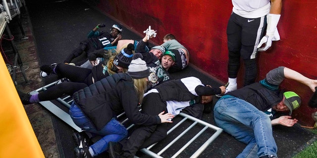 Fans lay on the ground after falling onto Philadelphia Eagles quarterback Jalen Hurts (1) as a railing collapsed following the end of an NFL football game, 日曜日, 1月. 2, 2022, ランドオーバーで, Md. Philadelphia won 20-16.
