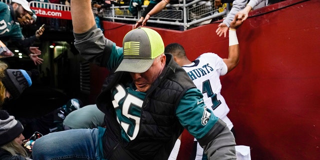 Fans pounce on Philadelphia Eagles quarterback Jalen Harts (1) after a railing fell at the end of a game on January 2, 2022 in Landover, MD.