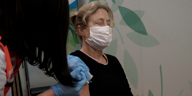 Esther Pamensky, a volunteer with the women's unit of United Hatzalah emergency service, administers a fourth dose of the COVID-19 vaccine to a woman at Clalit Health Services in Mevaseret Zion, Tuesday, Jan. 11, 2022.