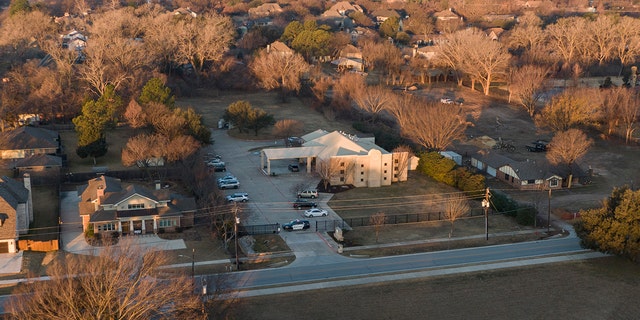 An aerial view of police standing in front of the Congregation Beth Israel synagogue, 日曜日, 1月. 16, 2022, in Colleyville, テキサス. 