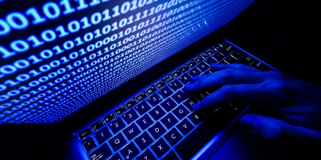 A hand on the keyboard is seen with binary code displayed on a laptop screen in this illustration photo taken in Krakow, Poland on Aug. 17, 2021. 