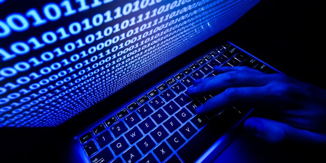 A hand on a keyboard is seen with binary code displayed on a laptop screen in this illustration photo taken in Krakow, Poland, Aug. 17, 2021. 