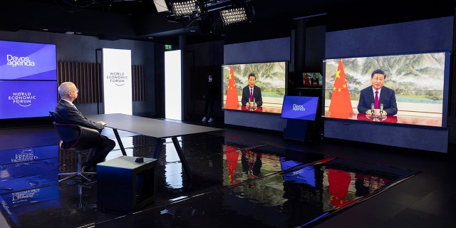 German Klaus Schwab, left, founder and executive chairman of the World Economic Forum (WEF), listens to Chinese President Xi Jinping displayed on a screen during the opening of the Davos Agenda 2022, in Cologny near Geneva, in Switzerland on Monday, January 17, 2022.