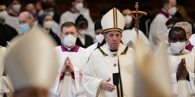 El papa Francisco camina con su personal pastoral entre cardenales y prelados con máscaras FFP2 al final de una misa de Epifanía en la Basílica de San Pedro en el Vaticano, el jueves 6 de enero de 2022. 