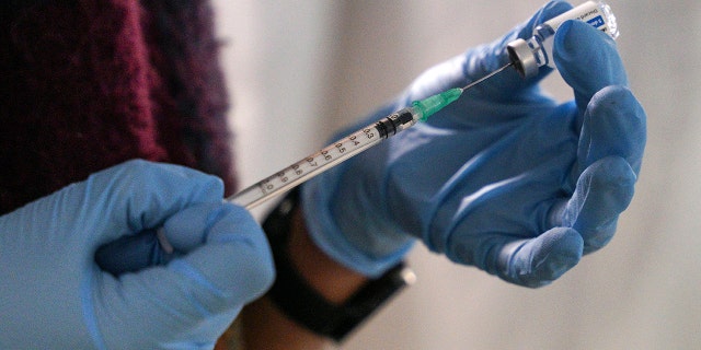 A staff member from the National Health Organisation (EODY) prepares a booster Johnson and Johnson vaccine against COVID-19 at Karatepe refugee camp, on the northeastern Aegean island of Lesbos, Greece, Wednesday, Dec. 15, 2021.