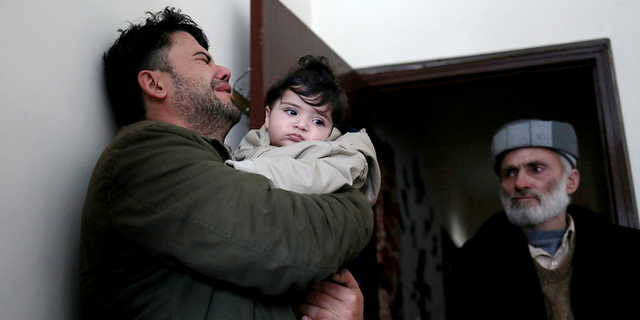 Hamid Safi, a 29-year-old taxi driver who had found baby Sohail Ahmadi in the airport, cries as he holds Sohail before handing him over to his grandfather Mohammad Qasem Razawi in Kabul, Afghanistan, January 8, 2022. Picture taken January 8, 2022. REUTERS/Ali Khara
