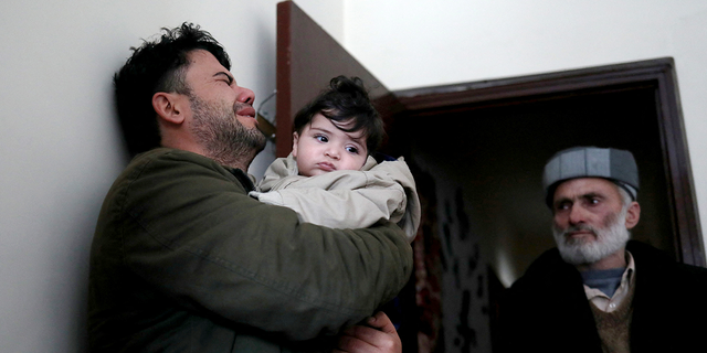 Hamid Safi, a 29-year-old taxi driver who had found baby Sohail Ahmadi in the airport, cries as he holds Sohail before handing him over to his grandfather Mohammad Qasem Razawi in Kabul, Afghanistan, January 8, 2022. Picture taken January 8, 2022. REUTERS/Ali Khara