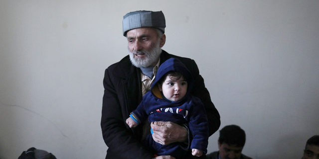 Mohammad Qasem Razawi, grandfather of baby Sohail Ahmadi, holds him at the house of Hamid Safi, a 29-year-old taxi driver who had found the baby in the airport, in Kabul, Afghanistan, January 8, 2022. Picture taken January 8, 2022. REUTERS/Ali Khara