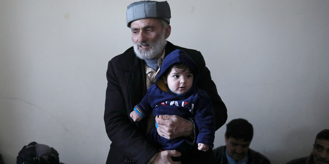 Mohammad Qasem Razawi, grandfather of baby Sohail Ahmadi, holds him at the house of Hamid Safi, a 29-year-old taxi driver who had found the baby in the airport, in Kabul, Afghanistan, January 8, 2022. Picture taken January 8, 2022. REUTERS/Ali Khara