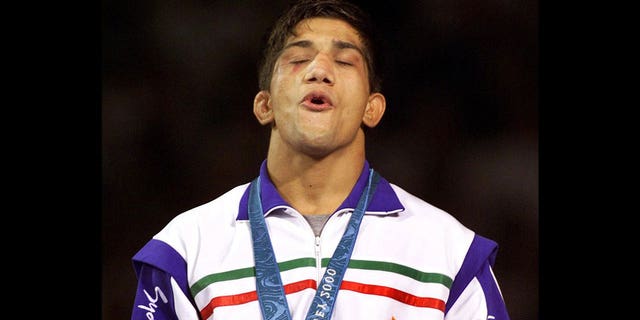 Alireza Dabir of Iran, receives gold medal for 58 kg Freestyle Wrestling at Sydney 2000 Summer Olympic Games, photo on black