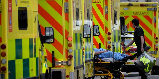 A patient is pushed on a trolley after arriving in an ambulance outside the Royal London Hospital in the Whitechapel area of east London, Jan. 6, 2022.