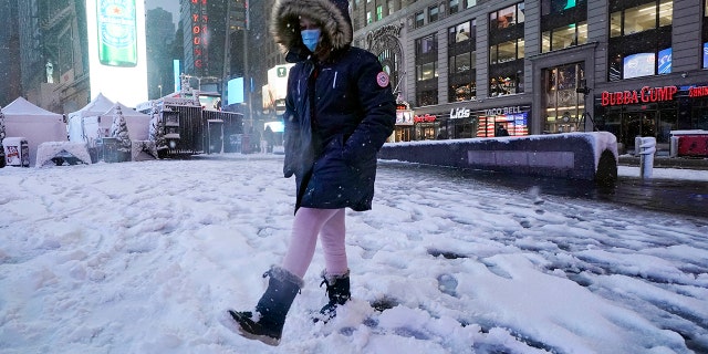 A girls kicks at snow in New York's Times Square, Friday, Jan. 7, 2022.