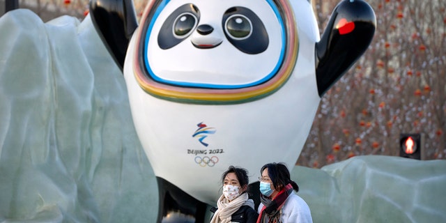 People wearing face masks to protect themselves from the coronavirus walk past a statue of Winter Olympic mascot Bing Dwen Dwen near Beijing Olympic Park on Wednesday, January 12, 2022.