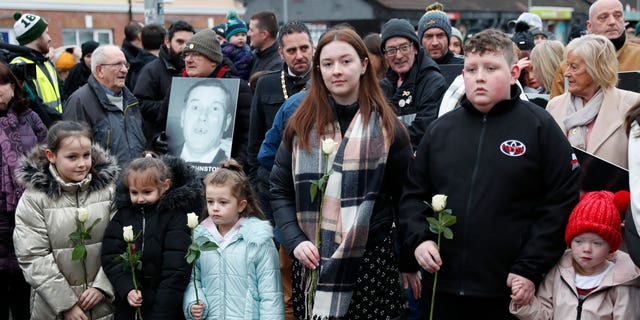 People take part in a march to commemorate the 50th anniversary of the Bloody Sunday shootings with photographs of some of the victims in Londonderry, Sunday, Jan. 30, 2022. In 1972, British soldiers shot 28 unarmed civilians at a civil rights march, killing 13 on what is known as Bloody Sunday or the Bogside Massacre. Sunday marks the 50th anniversary of the shootings in the Bogside area of Londonderry. 