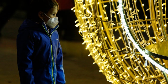 Um menino com uma máscara facial observa as luzes de Natal em Granada, Espanha, em meio à pandemia de coronavírus em 20 de dezembro de 2021.
