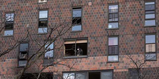 A person works to cover the window frame in the apartment building which suffered the city's deadliest fire in three decades, in the Bronx borough of New York on Monday, Jan.. 10, 2022. 