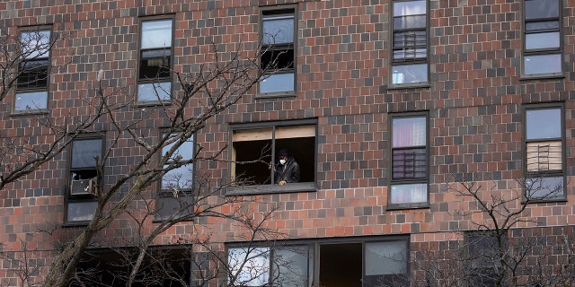 A person works to cover the window frame in the apartment building which suffered the city's deadliest fire in three decades, in the Bronx borough of New York on Monday, Jan.. 10, 2022.