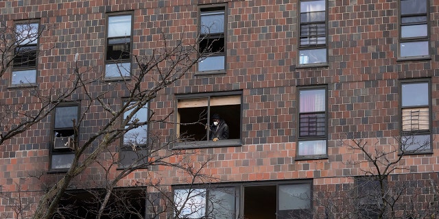 A person works to cover the window frame in the apartment building which suffered the city's deadliest fire in three decades, in the Bronx borough of New York on Monday, Jan. 10, 2022. 