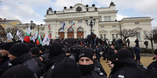 Police officers line up as they try to keep protesters away from the Bulgarian Parliament building in Sofia, Wednesday, Jan. 12, 2022.