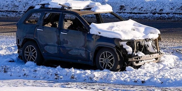 Snow covers the burned remains of a car after wildfires ravaged the area Sunday, Jan. 2, 2022, in Superior, Colorado.