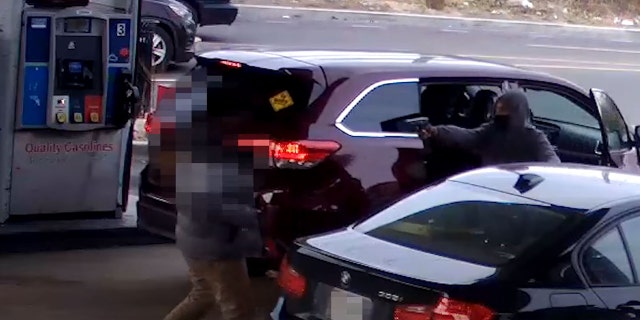 A still image from surveillance video released by Washington, D.C.'s Metropolitan Police Department shows a suspect point a gun at a driver before hijacking his car.