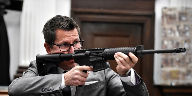 FILE- Assistant District Attorney Thomas Binger holds Kyle Rittenhouse's gun as he gives the state's closing argument in Kyle Rittenhouse's trial at the Kenosha County Courthouse in Kenosha, Wis., on Monday, Nov. 15, 2021.