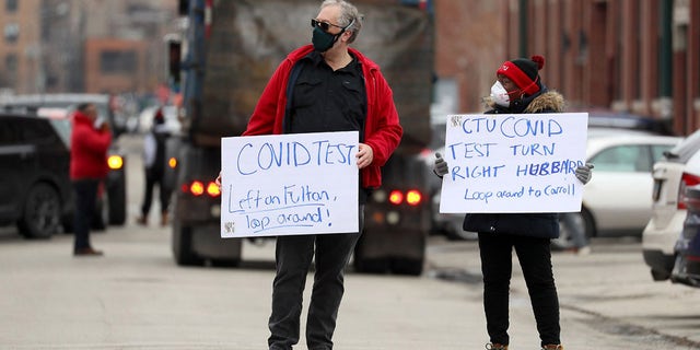 Chicago Teachers Union workers direct cars lined up for COVID-19 testing outside of CTU headquarters on Thursday, 12月. 30, 2021.